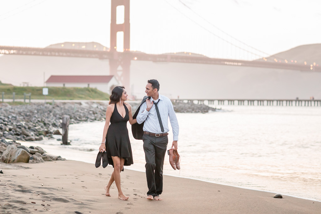 couple walking along the water at Crissy Field wearing suit and black cocktail dress