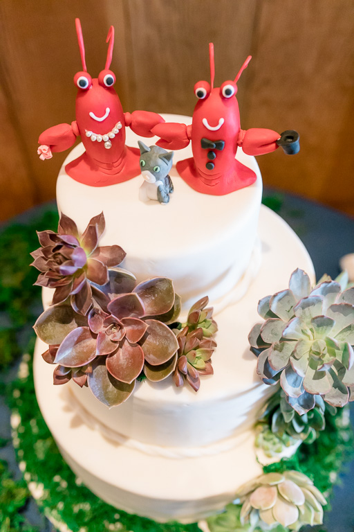 Wedding cake with two lobster toppers and a cat