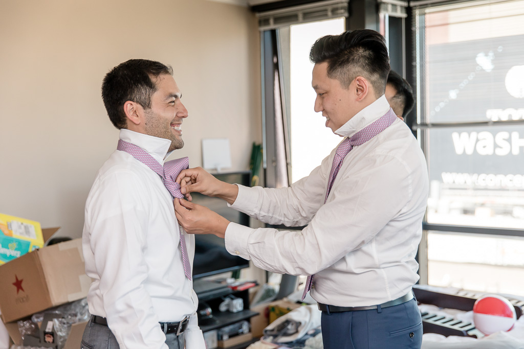 groom getting his tie tied by a groomsman