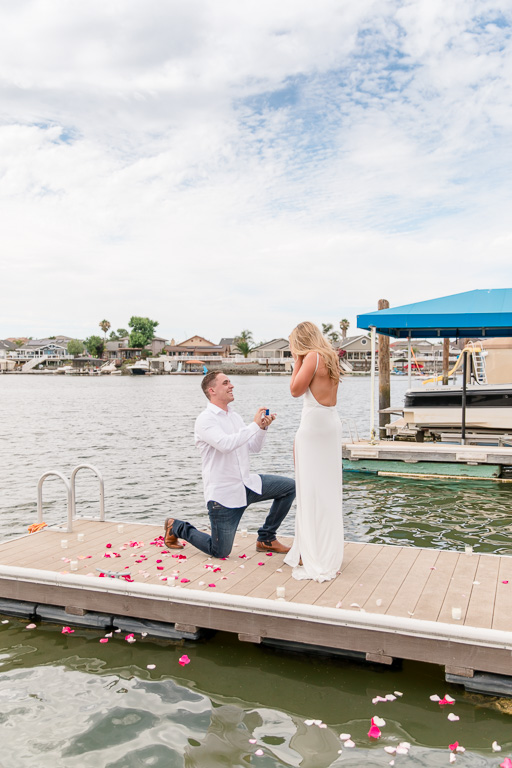 surprise proposal on lakehouse dock decorated with rose petals