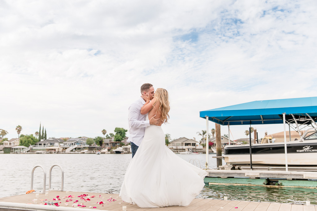 couple kissing on a boat dock with rose petals on the ground