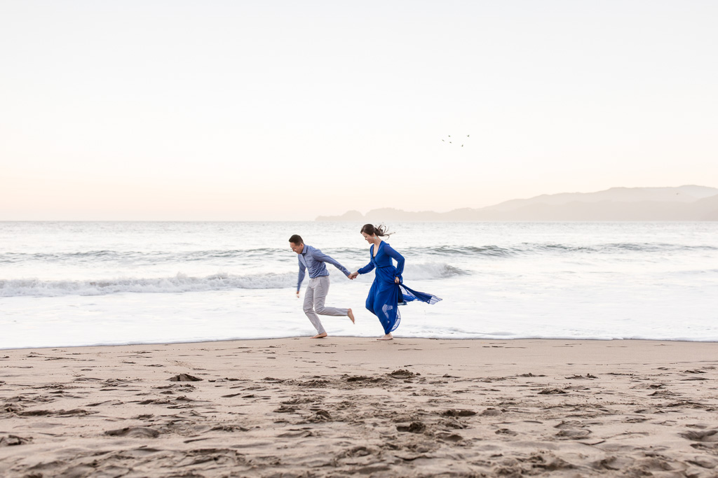running around and kicking water during their san francisco beach engagement session
