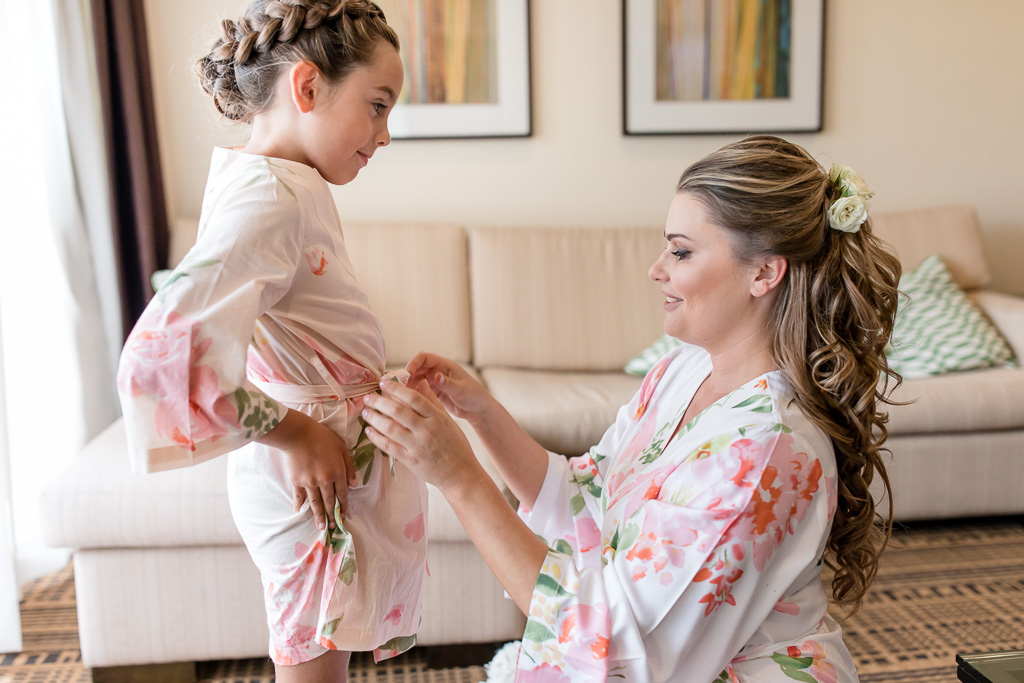 bride helping the flower girl with her floral robe