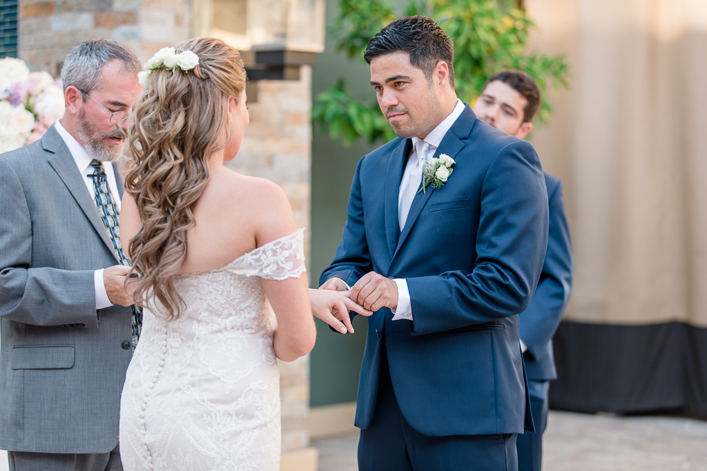 groom putting the ring on bride's finger