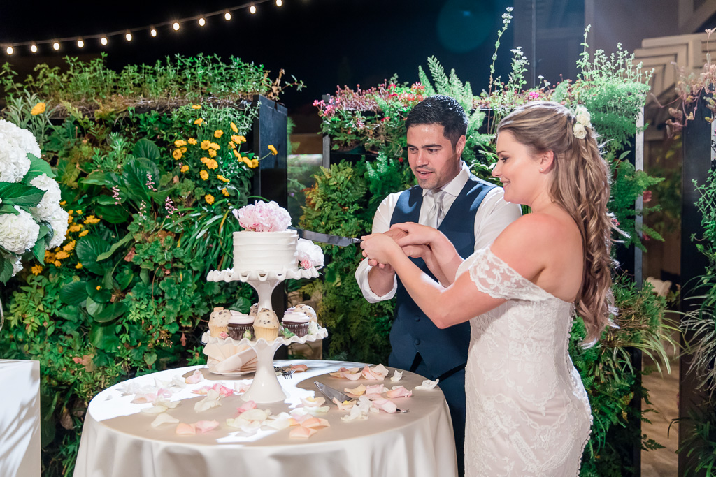 cake cutting in front of a flower wall