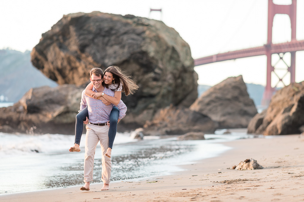 Marshall's Beach piggyback ride engagement photo Golden Gate Bridge view