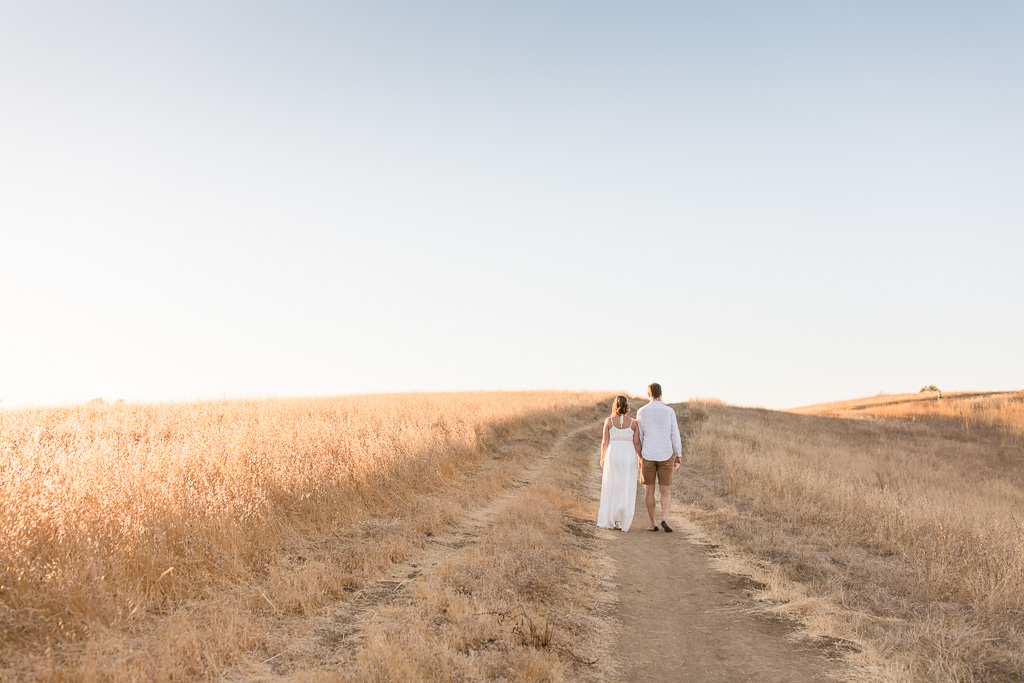 couple walking on a yellow field at sunset