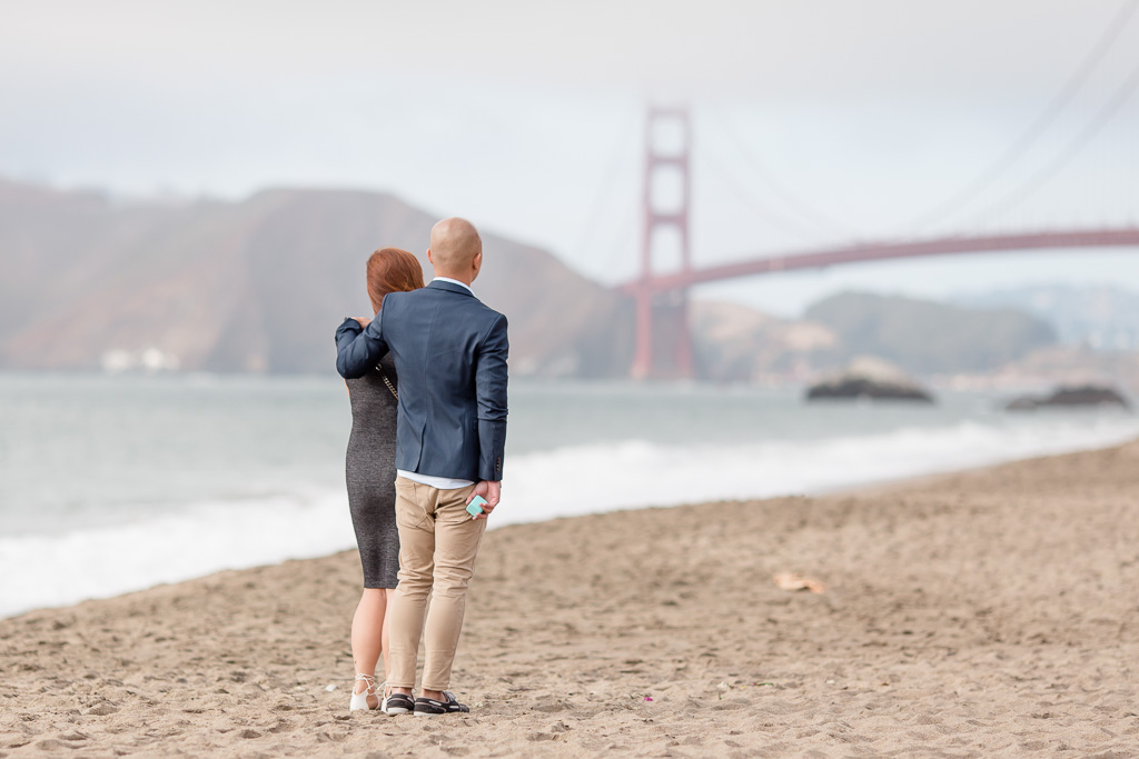 guy hiding a tiffany ring box for the surprise proposal on baker beach