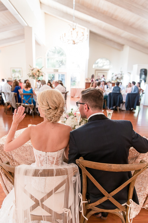 couple waving at guests from their sweetheart table