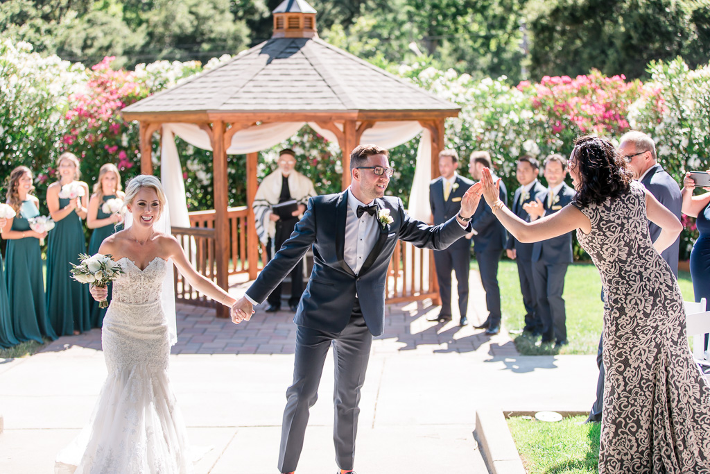 high five with wedding guests during ceremony recessional