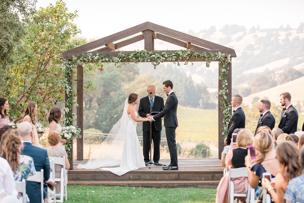 a beautiful wedding ceremony under the wooden gazebo at the highlands estate in cloverdale