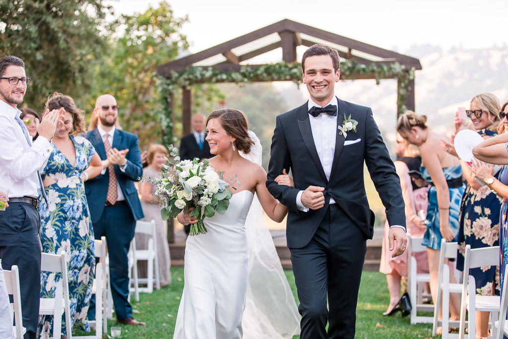 happy newlyweds walking down the aisle at the highlands estate