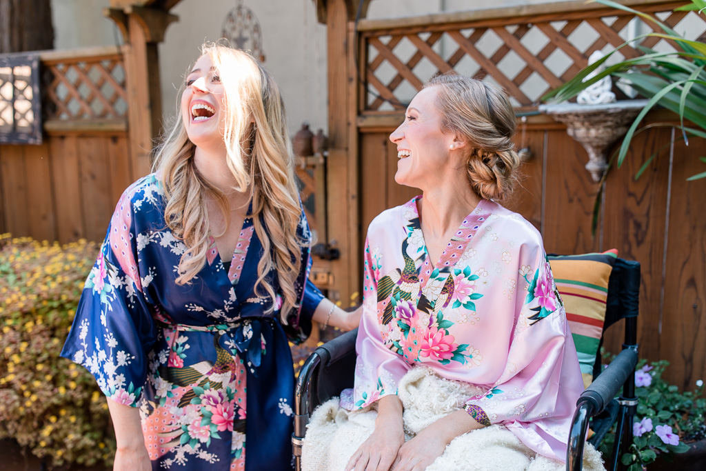bride and bridesmaid laughing while getting ready