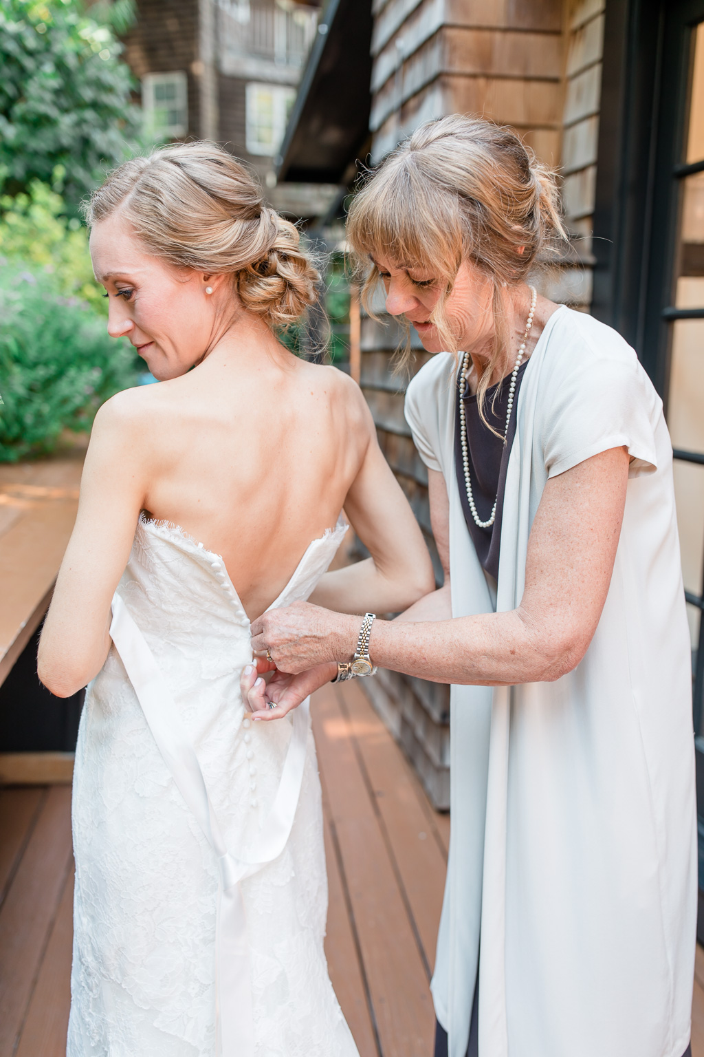 mother of bride helping her zip up the dress