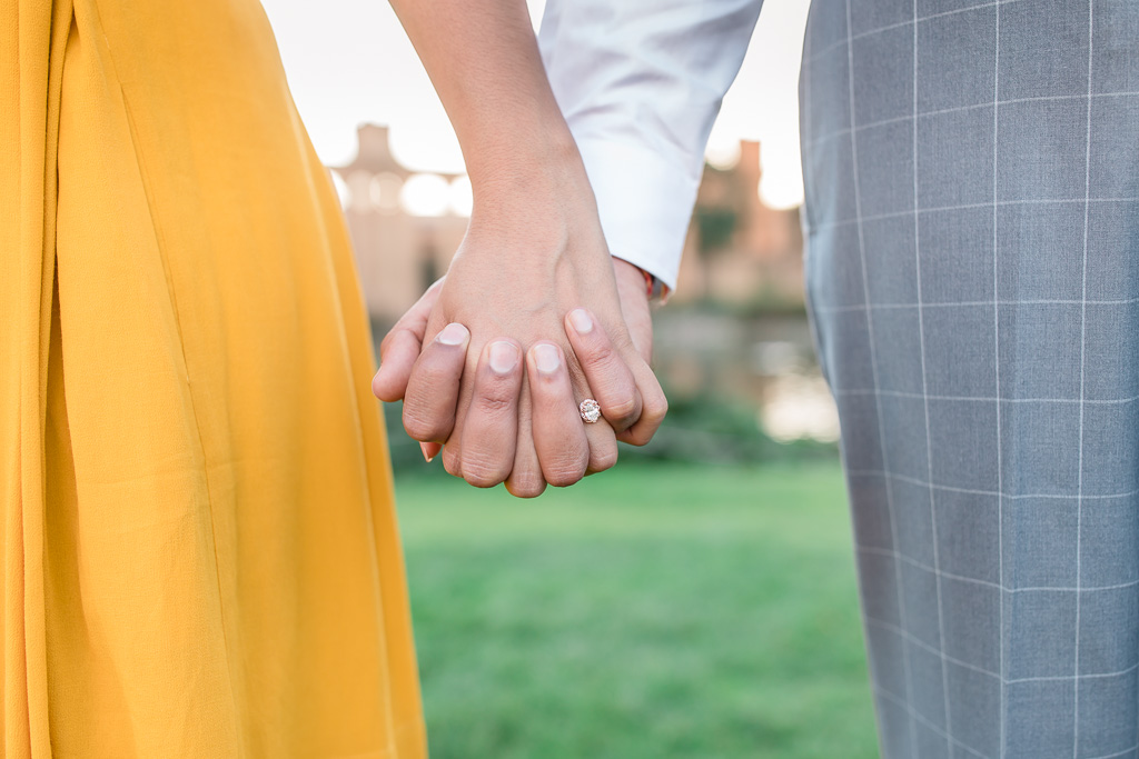 close up of couple holding hands showing engagement ring
