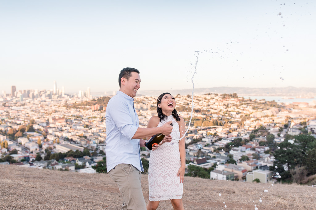 having fun uncorking champagne at engagement session