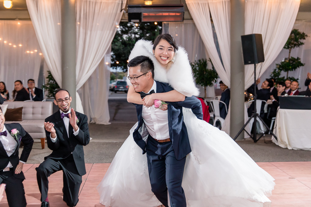 groom carrying the bride on his back running into the reception
