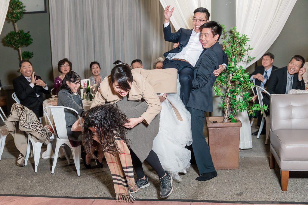 wedding guests carrying bride and groom to the center of the dance floor