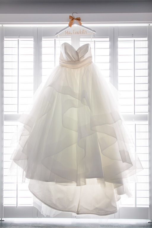 a stunning Hayley Paige wedding gown hanging on a window