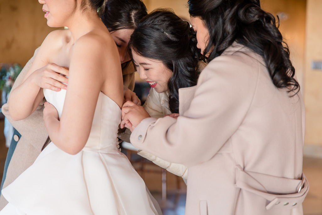 bridesmaids zipping the bride up