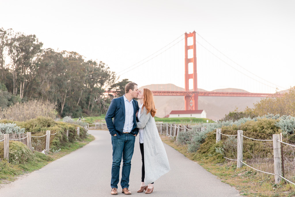 engaged couple kissing in front of the golden gate bridge
