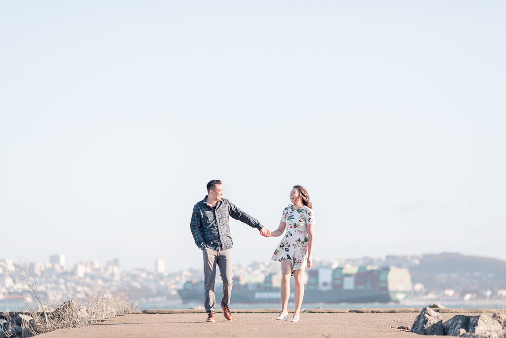 photo of couple walking with the city skyline in the background