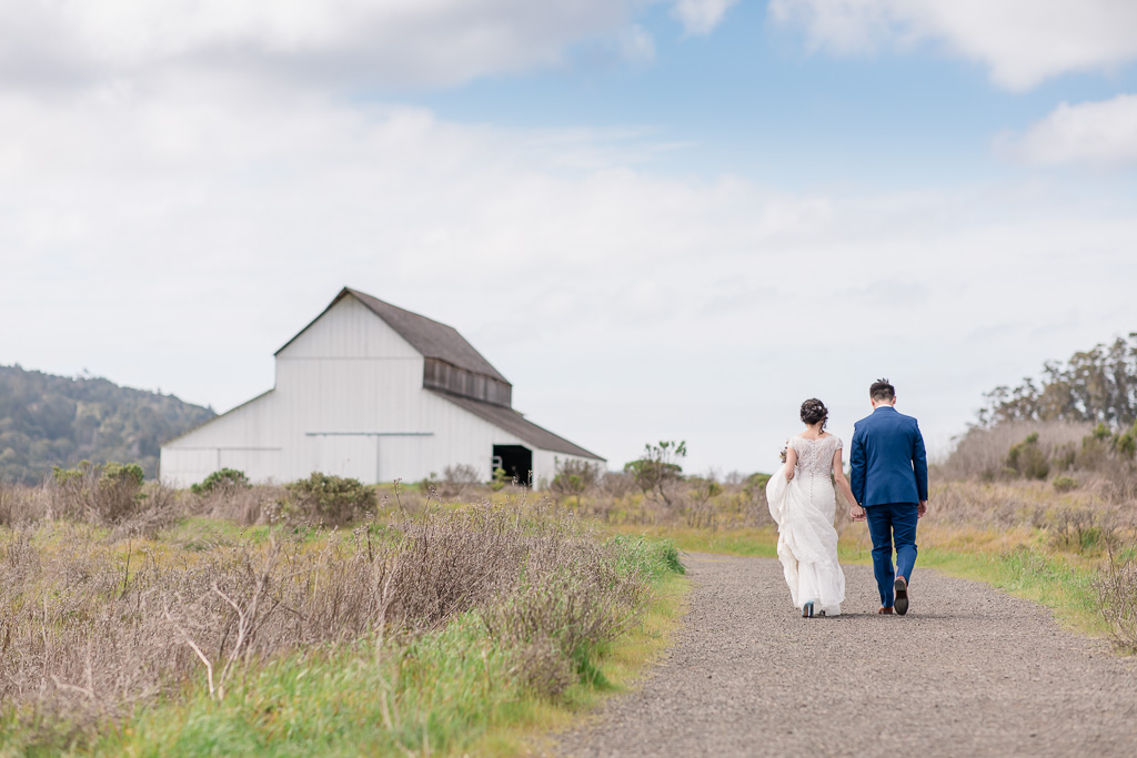 newlyweds walking towards a cute barn