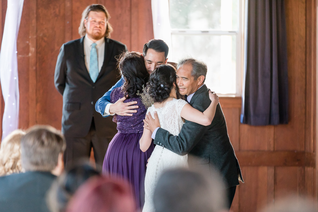 bride and groom hugging their parents