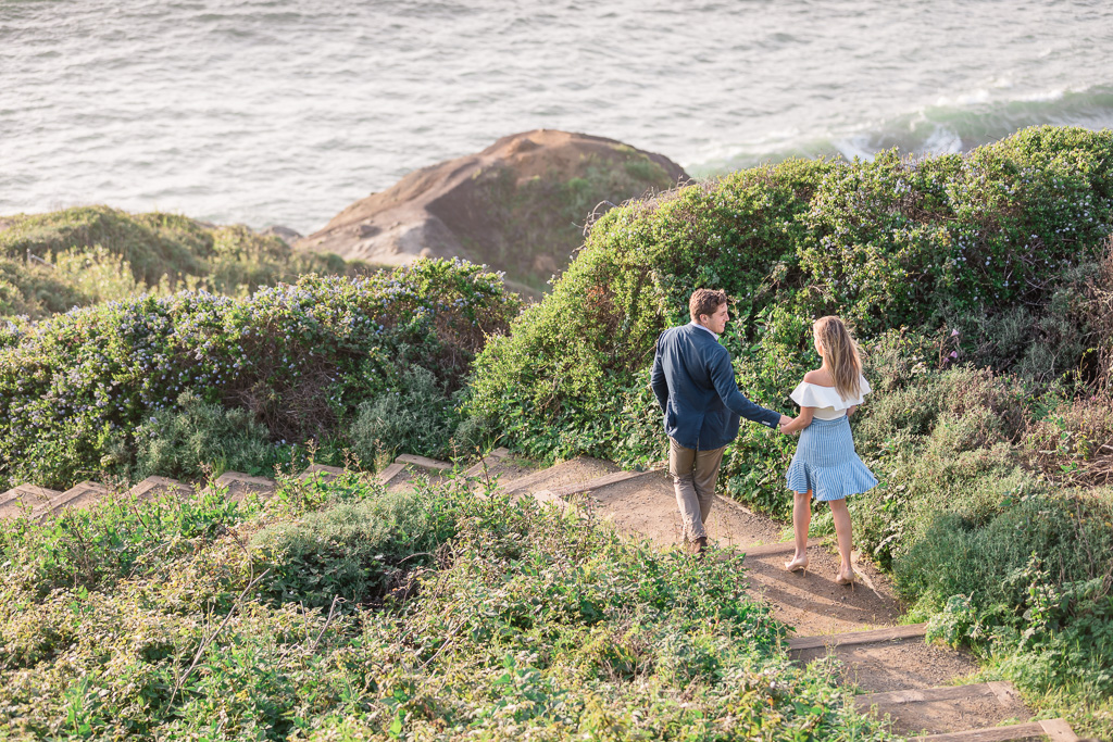 candid engagement photo hiking trail down to the ocean