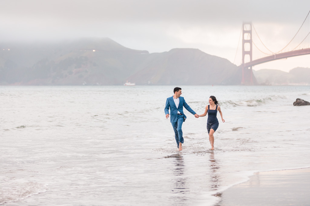 couple running along San Francisco beach ocean shoreline