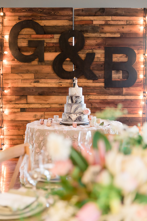 pretty marble wedding cake presentation in front of a huge customized wooden backdrop
