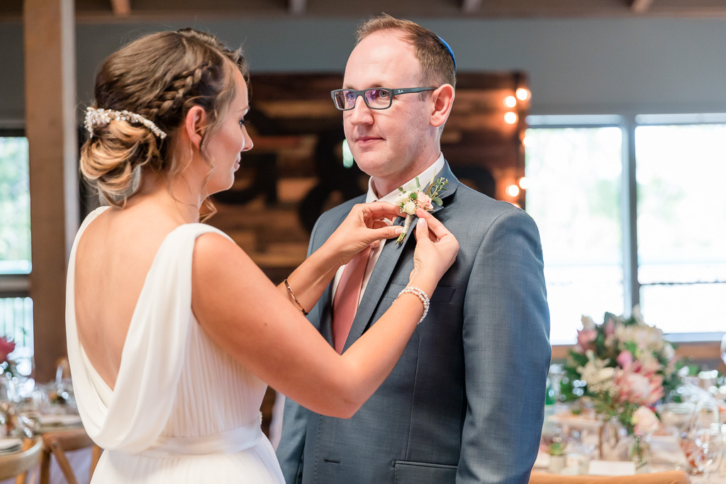 bride pinning the boutonniere for the groom