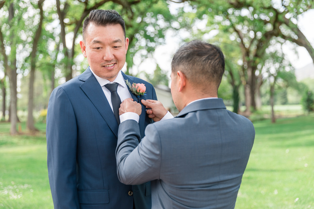 groomsman helping groom with his boutonnière