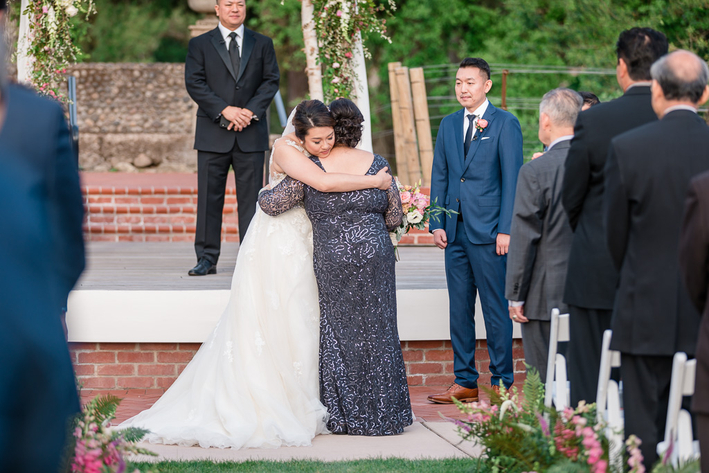 mom and bride hugging at the end of the aisle before wedding ceremony