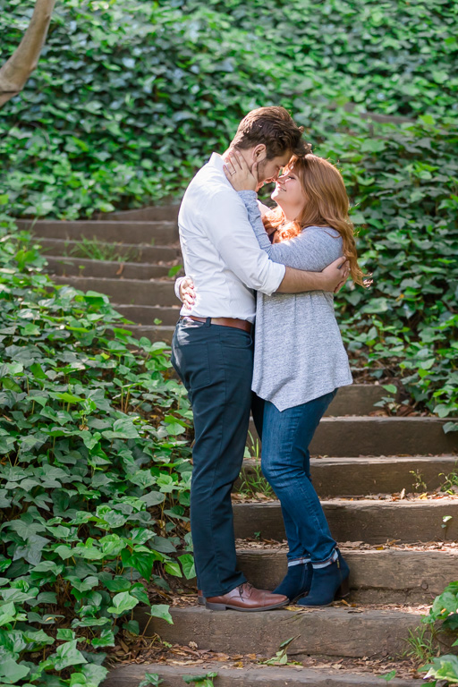 sun-lit engagement photo in the woods on stairs