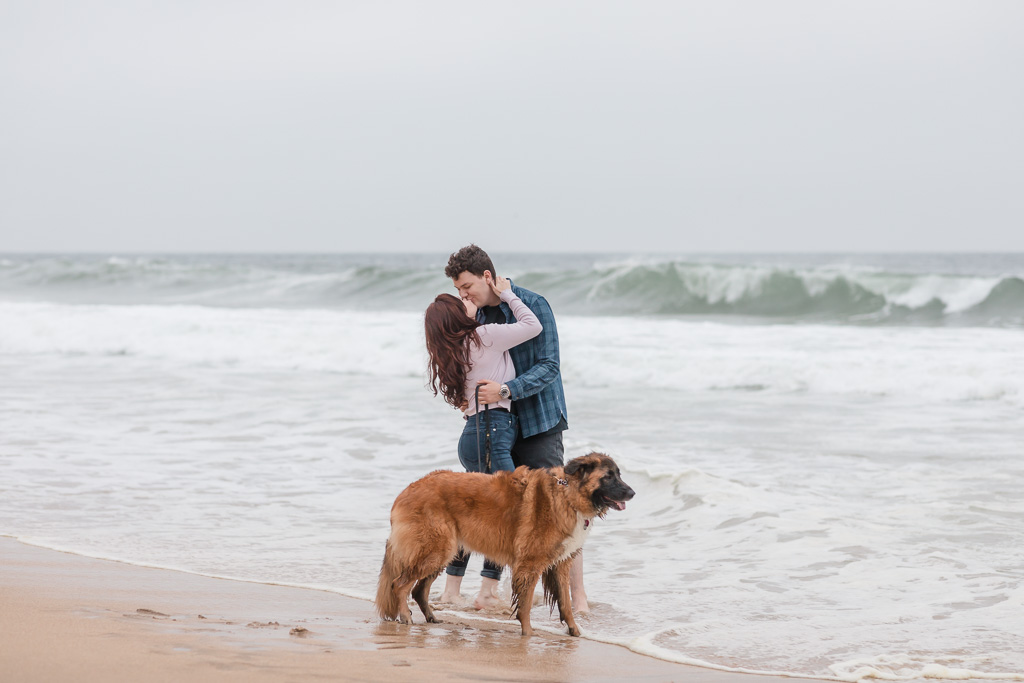 kissing photo of the couple behind their dog