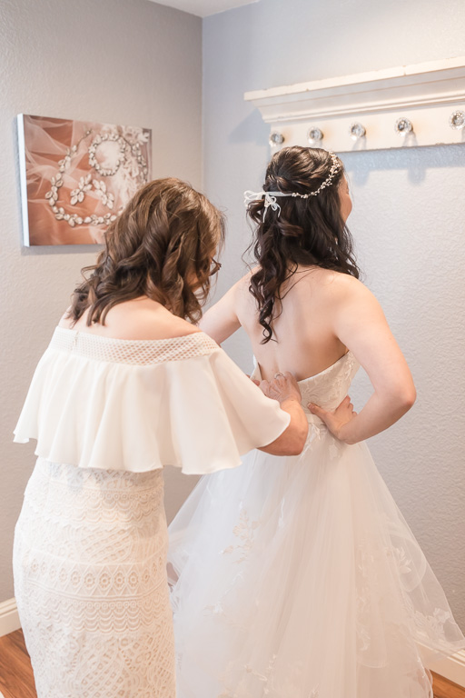 mom helping the bride with her dress
