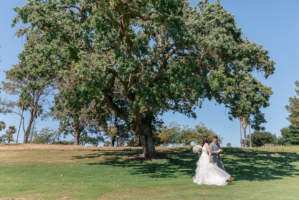 wedding first look next to a big oak tree on a golf course