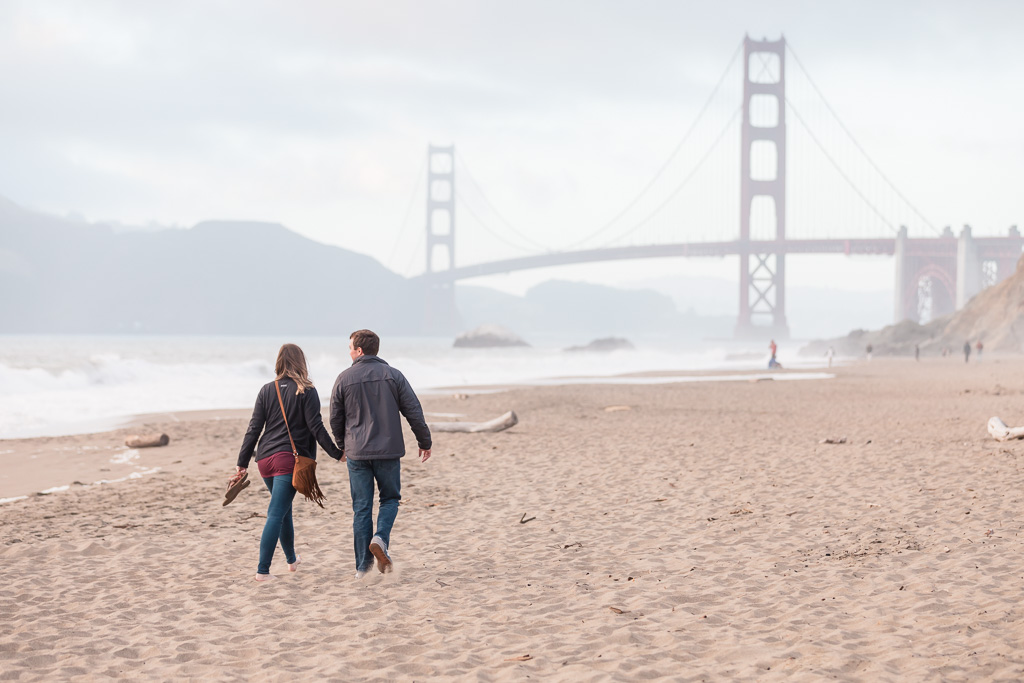couple strolling down the beach to their golden gate bridge proposal spot
