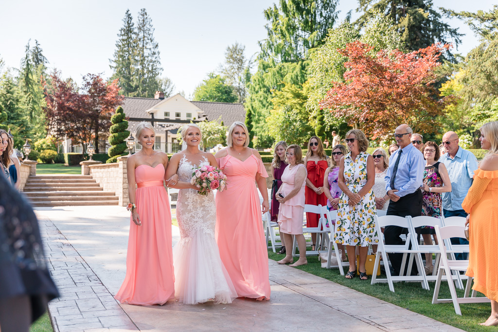 bride walks down the aisle escorted by her sisters