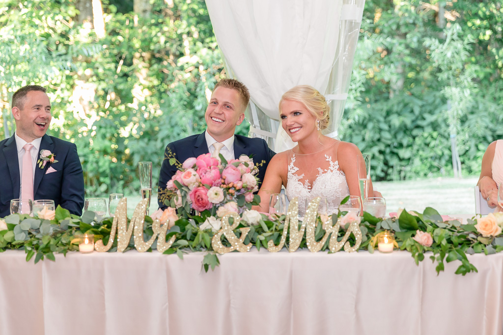 bride and groom at their head table under the tent