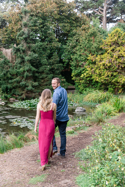 engagement photo walking along the path by the pond