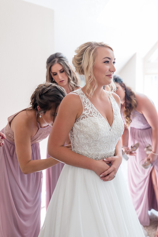 ladies helping bride to get into her dress