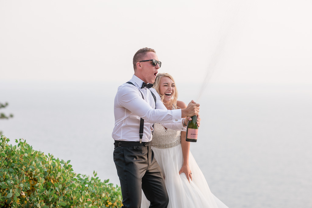 super fun wedding moment - bride and groom opening and uncorking a bottle of champagne