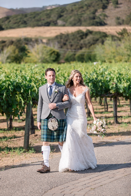 newlyweds walking along the vineyards to their reception