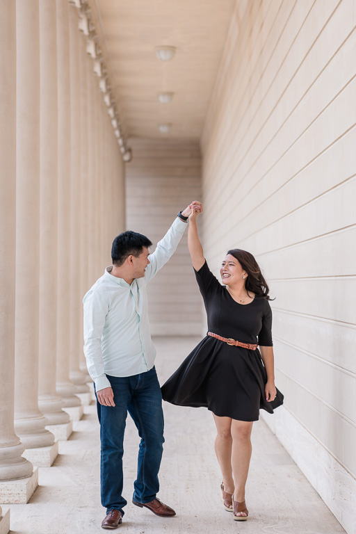 engagement picture walking and twirling in between the columns