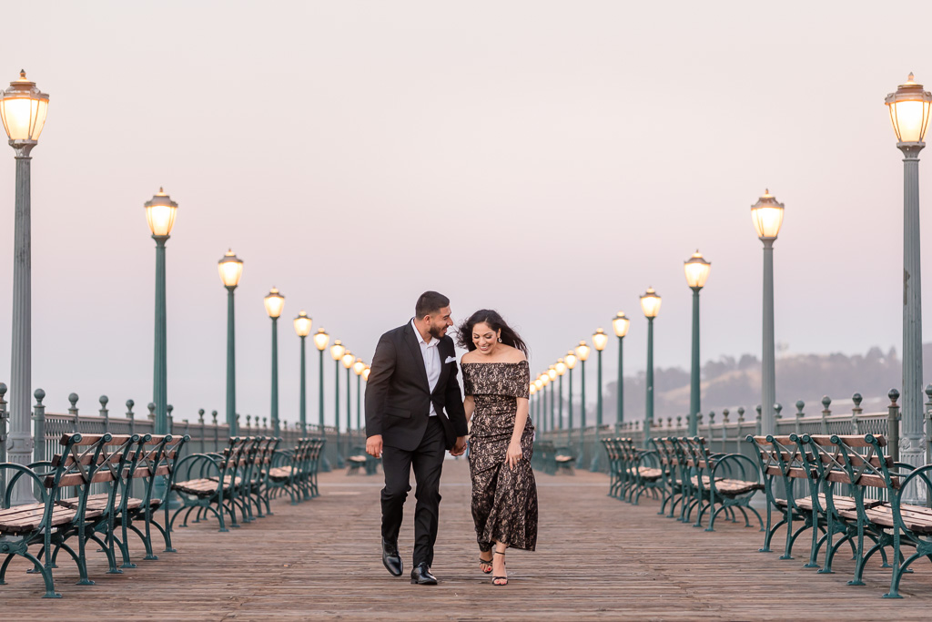 candid walking couple engagement photo on the pier at dusk