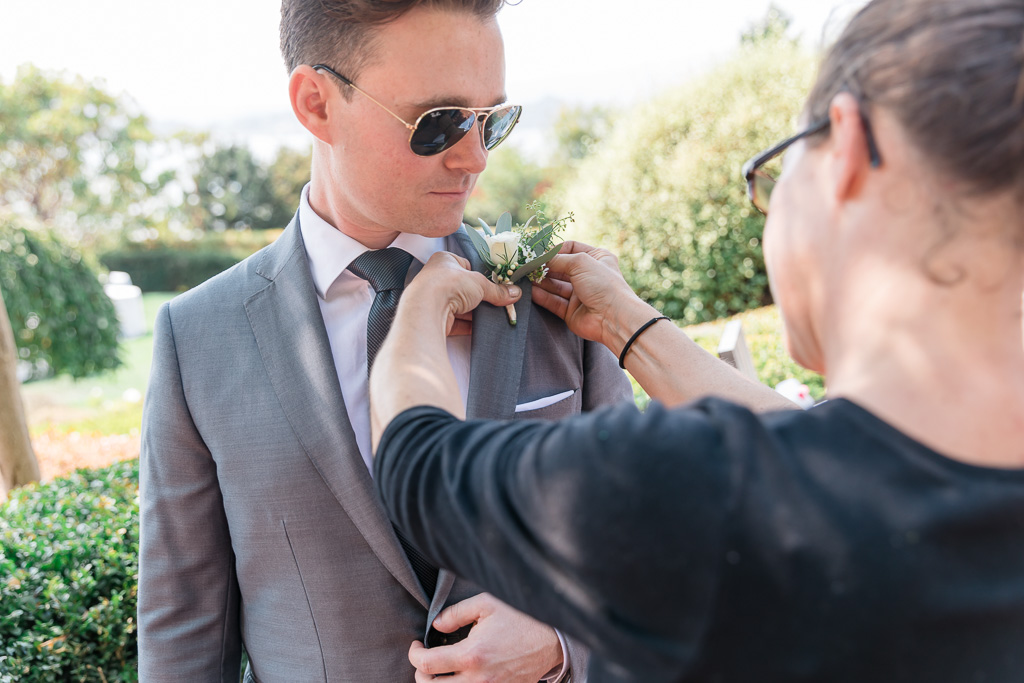 Groom getting boutonnière pinned on