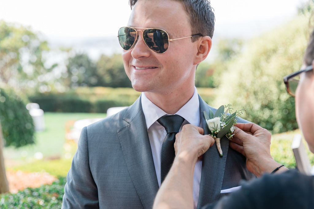 pinning boutonnière on the groom's suit jacket lapel