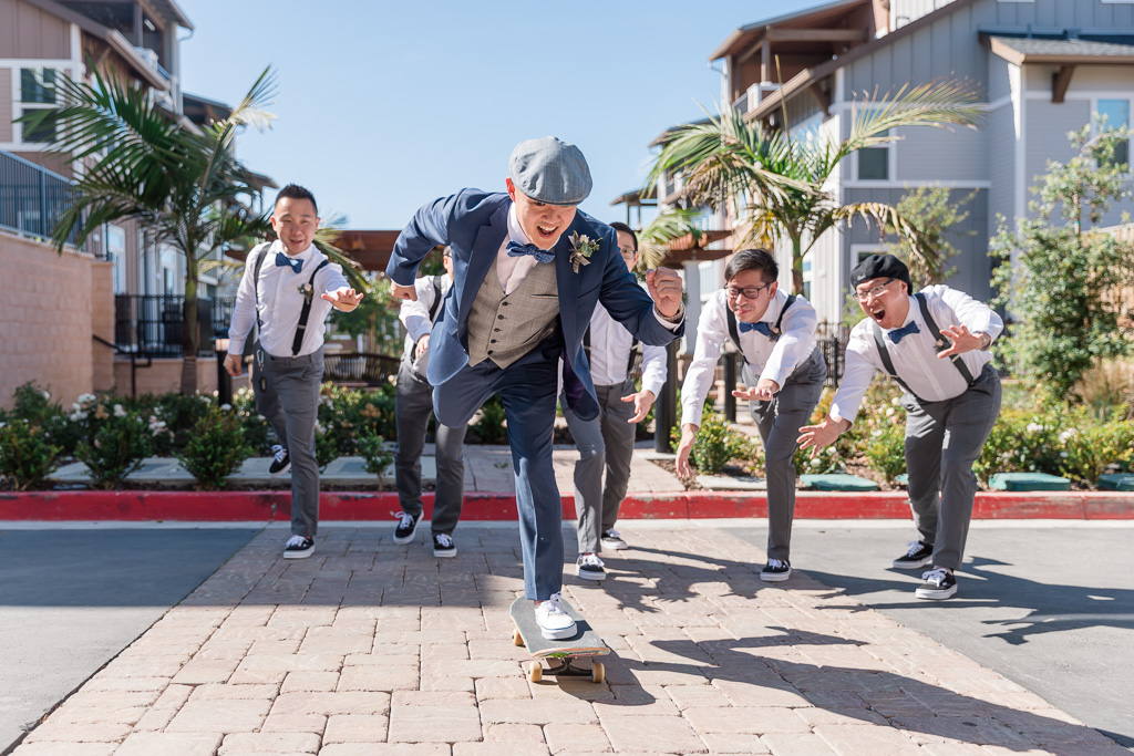fun photo of groom on a skateboard with groomsmen behind him